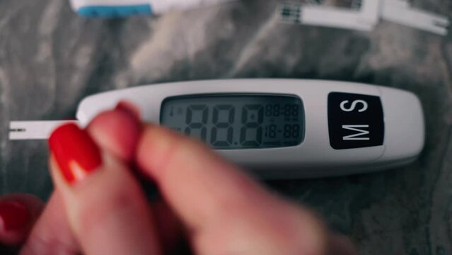 The patient measures blood sugar. The person performs the analysis using a glucometer with a test strip. A digital sugar meter counts down and shows the result. High sugar. Hyperglycemia.