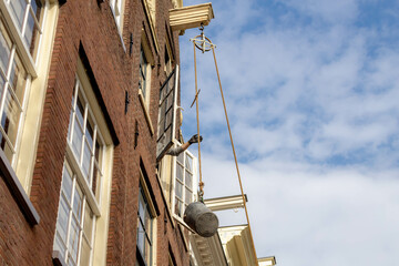 Fototapeta na wymiar Amsterdam traditional houses, Pretty Dutch style gable roof tops under blue sky with pulley and rope, Lifting beam and wheel for transporting items into or out of a tall house, Netherlands. 