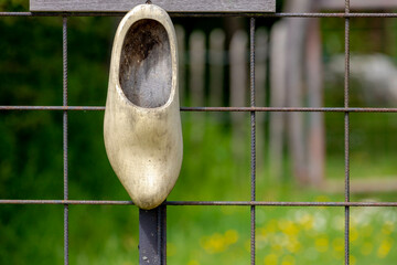 Traditional old wooden shoe or clog hanging as decoration on front door iron gate in farmhouse, One...