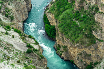 top view of a fast mountain river flowing at the bottom of a deep canyon