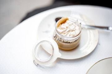 Tiramisu dessert in glass jar at restaurant table. Classic Italian dessert serving