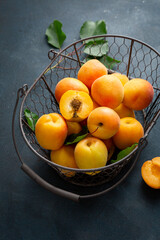 Close up of fresh whole apricots and half in basket