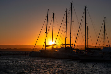 Panoramic view during sunset on the harbor of Ortigia island in the city Syracuse, Sicily, Italy, Europe, EU. Boat and yachts flowing in the Siracusa bay in the Mediterranean Sea. Vacation seaside