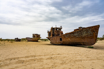 Fototapeta na wymiar Boats cemetery around the Aral Sea. Rusty carcasses in the desert dunes where once there was water.