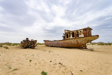 Fototapeta na wymiar Boats cemetery around the Aral Sea. Rusty carcasses in the desert dunes where once there was water.
