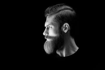 Black and white portrait of confident young bearded man looks into the distance. Side view portrait...