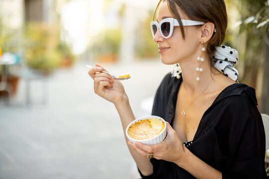 Woman eating dessert with creme brulee at the restaurant outdoors. Concept of italian cuisine