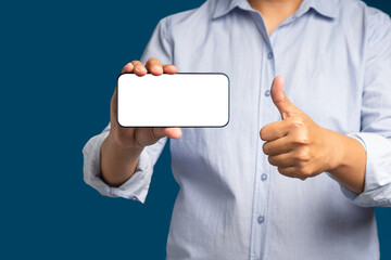 Hand holding a horizontal mobile phone with a blank white screen and showing thumbs up while standing on a blue background