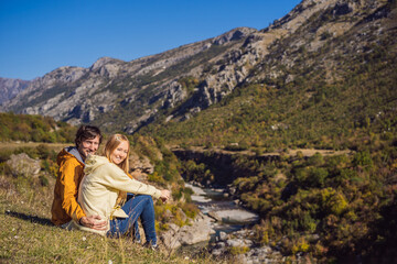 Naklejka na ściany i meble Montenegro. Happy couple man and woman tourists on the background of Clean clear turquoise water of river Moraca in green moraca canyon nature landscape. Travel around Montenegro concept