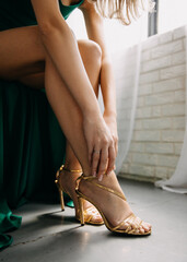 Closeup of a woman putting on her golden sandals.