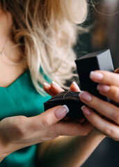 Closeup of female hands opening a jewelry box with an engagement diamond ring.