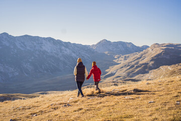 Fototapeta premium Montenegro. Mom and son tourists in the background of Durmitor National Park. Saddle Pass. Alpine meadows. Mountain landscape. Travel around Montenegro concept