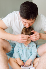 Young father caring his daughter touching her hairs while she playing