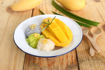 Thai famous delicious dessert - Closeup plate of sweet fresh ripe mango with three color of sticky rice , green from pandan and purple from butterfly pea flower