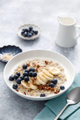 Oatmeal porridge with banana, blueberries, pecan nuts and sesame seeds