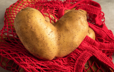 Heart shaped ugly potato on red string bag