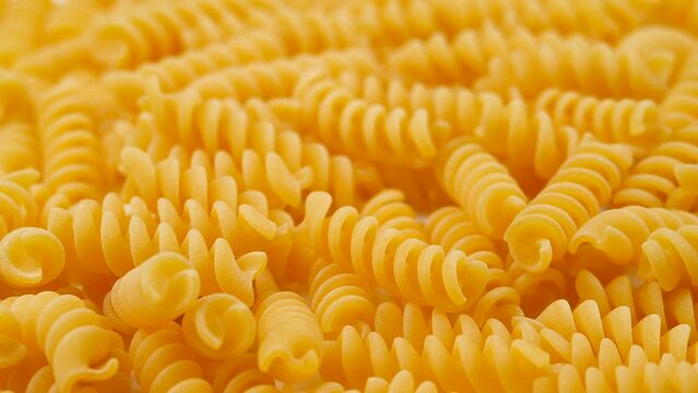 Background Of Fusilli Pasta. Uncooked Italian Pasta Golden Rotating Backdrop. Healthy Eating Concept. Raw Dried Organic Pasta. Spiral Macaroni, Rotating Background. Italian Culture and Cuisine Pattern