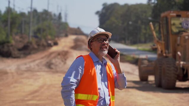 Asian Engineer or Investor and Worker working on 
Road construction works with Excavator and roller compactor machine on a road construction site.
