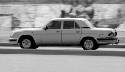 The retro car is driving along the road. High driving speed. Fast car driving.