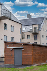 Brown wooden scandinavian style storehouse in fron of the modern apartment building