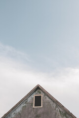 Old house on the background of a beautiful sky. Clouds on the blue sky. Bright sunny day in the village.
