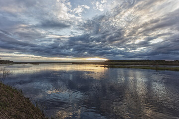 Obraz premium Beautiful bright sunset over the river with amazing reflection in the water.
