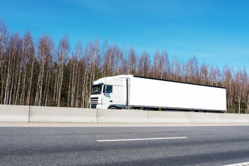 Delivery truck with long empty banner for mockup drives on highway. Transportation logistic concept.