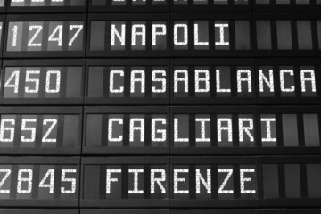 Flight destinations - airport departure board in Italy. Black and white vintage style photo.