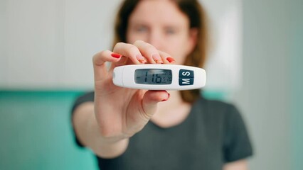 Diabetes testing equipment. Patient with diabetes using a blood glucose meter. Upset girl shows the camera a glucometer with high blood sugar. Uncontrolled diabetes. Decompensation. Hyperglycemia