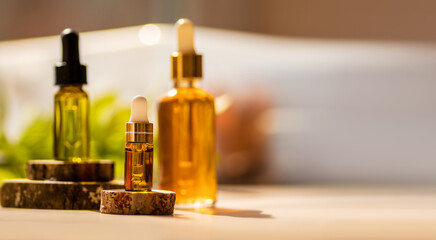 Cosmetic glass dropper bottles on wooden podium with oil, serum, fruit peeling in the sunlight....