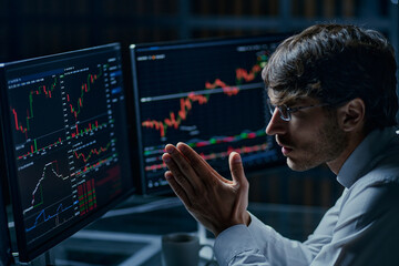 businessman looking at computer monitors with stock market data .