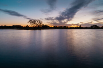 Obraz premium Evening colourful clouds after sunset over a calm lake
