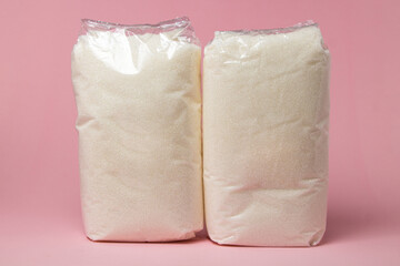 Sugar in a transparent package on a pink background. Packed sugar. Essential item