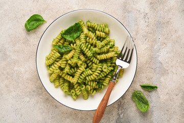 Italian Fusilli Pasta with Pesto. Fusilli pasta with basil pesto and herbs, parmesan cheese, basil and garlic on white plate on grey stone countertop background. Top view. Copy space. Mock up.