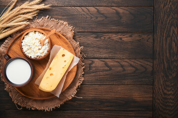 Happy Shavuot. Background for Shavuot traditional religious Jewish celebration. Milk and cheese, ripe wheat and fruits. Dairy products over old brown wooden background. Shavuot concept. Top view.