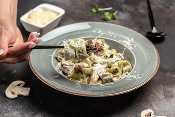 Pasta fettuccine with mushrooms and fried chicken ham in creamy cheese sauce on dark background. Restaurant menu, dieting, cookbook recipe top view