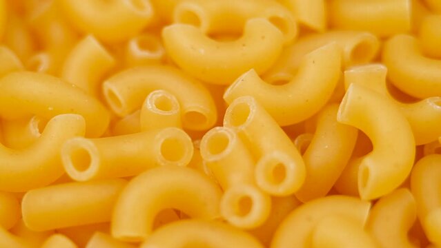 Background Of Chifferi Rigati Pasta. Uncooked Italian Pasta Golden Rotating Backdrop. Healthy Eating Concept. Raw Dried Organic Pasta.  Bent Tubular Macaroni, Rotating Background. Italian Culture