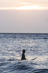 Silhouette of lsurfer woman on the beach at sunset.