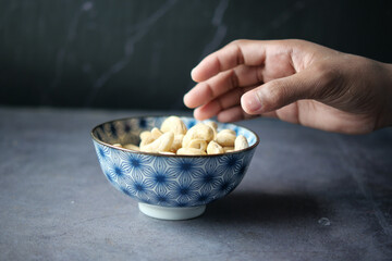 hand pick cashew nut from a bowl on table 