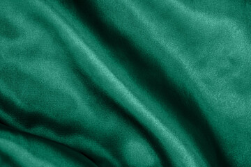 Elegant smooth green silk or satin folds closeup. Cloth texture background. Abstract wallpaper. Trendy mint green backdrop for web design. Luxury twisted fabric backplate 