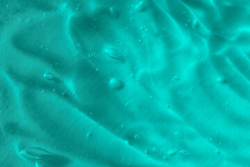 Texture of transparent antiseptic gel with air bubbles on blue background. Summer ocean imitation. Concept of skin moisturizing, prevention of virus. Liquid beauty product closeup. Backdrop, flat lay