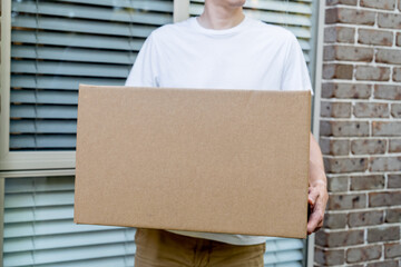 Parcel box delivered to a front door of residential building by delivery courier man. Online...
