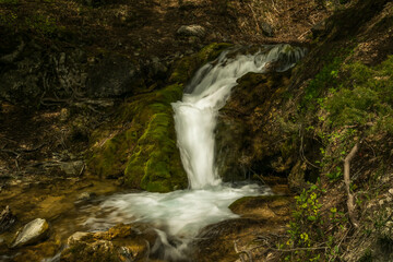 Fototapeta premium waterfall in the mountains with moss and rocks around