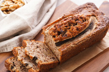 Fototapeta na wymiar Chocolate banana bread with walnuts on a wooden board and ingredients on a grey neutral background