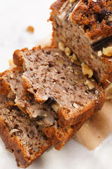 Chocolate banana bread with walnuts on a marble board and ingredients on a grey neutral background