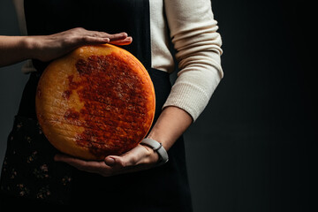 craftsmanship hands have a typical Italian cheese. French tomme cheese in the hands of a cheesemaker on dark background. Different homemade cheeses. Long banner format