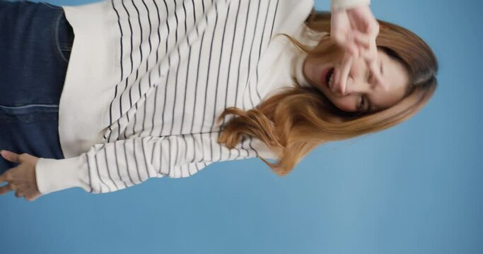 Closeup youth Asia lady pretty cheerful wear sweater over blue isolated background overjoyed excited funny dancing  with smiling enjoy happy moment. Dancing standing raising hands. Vertical screen.