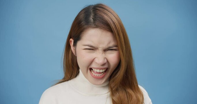 Portrait of a frustrated angry pensive Asia lady open mouth scream out loud isolated on the blue background. Crazy female bad mood argument shouting at boyfriend, Negative emotions and feeling.