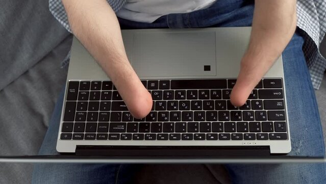 Disabled man with amputated two stump hands working typing on laptop at home sitting on sofa, hands closeup. Problem of adaptation to life people with disabilities. Independent Invalid person.