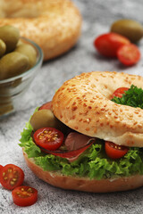 Sesame bagels with tomatoes, ham and olives